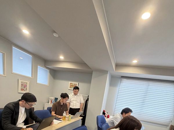 明るい教室で参加者の作業を見て回る講師